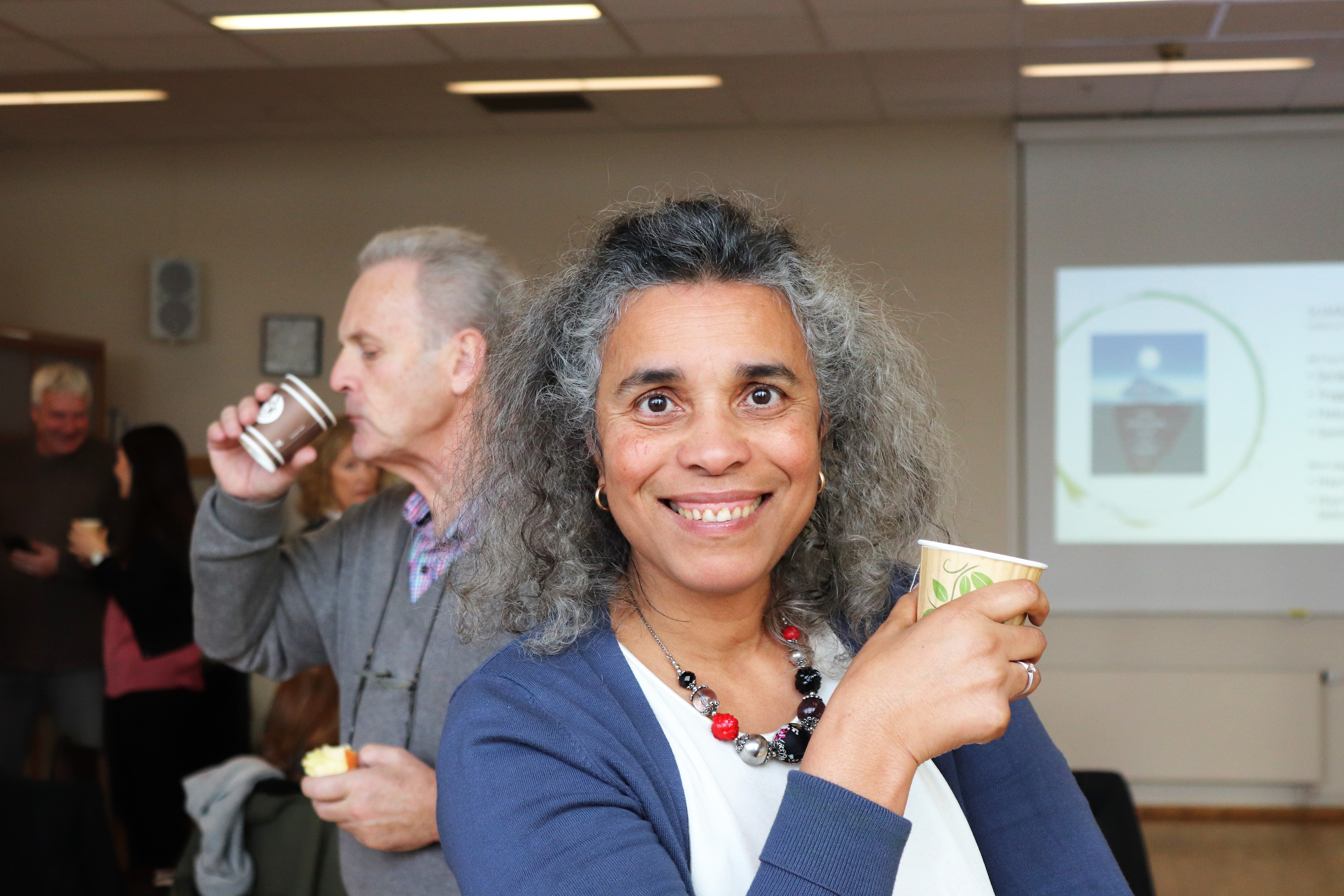 Foto av fornøyd medarbeider, dame med kaffekopp i møtelokale